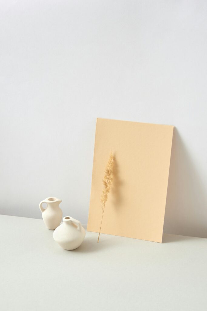 Elegant minimalist setup with ceramic vases and artwork on a neutral background.